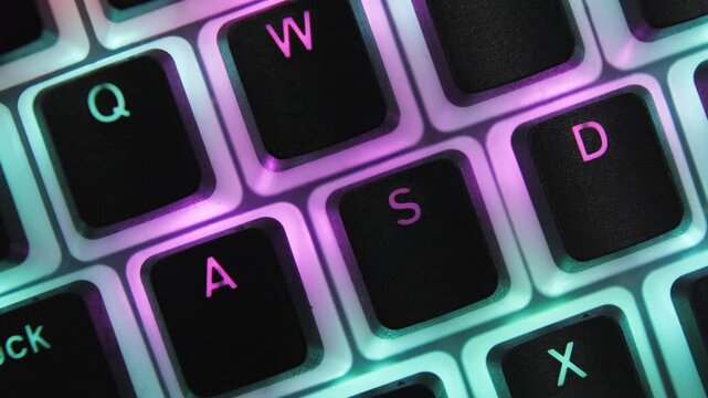 WASD game control buttons neon purple backlight stand out against turquoise backlit computer gaming keyboard