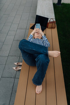Woman relaxing on bench checking smartphone