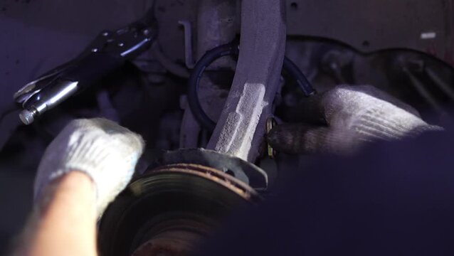 Mechanic secures a new brake hose bracket to suspension arm.