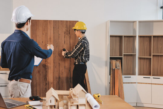 Asian architect and engineer team checking architectural house model using measuring tape on the table at office studio.