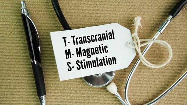 Stethoscope and paper with the word transcranial magnetic stimulation. safe, noninvasive medical procedure that uses magnetic pulses to stimulate nerve cells in targeted areas of the brain