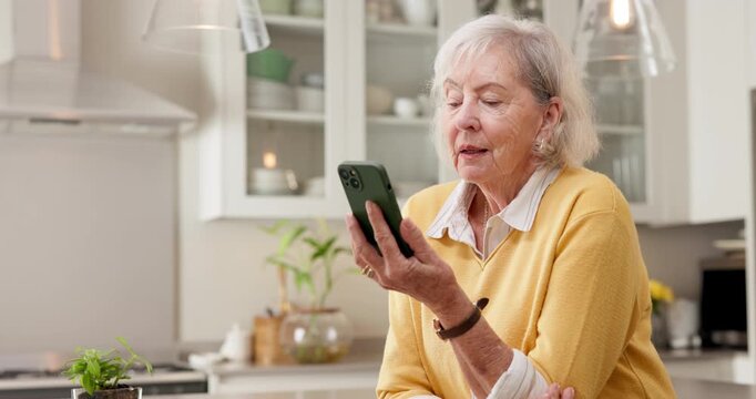 Senior, wave and happy woman with phone for video call, conversation or friendly chat in kitchen. Elderly, female person or hello with smile or discussion for communication or virtual talk in home