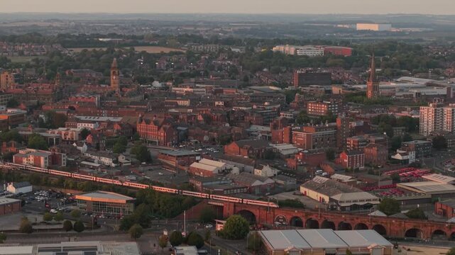Drone POV of Wakefield city and moving long train on the viaduct in sunset. Aerial view of Wakefield, a cathedral city located on the River Calder in West Yorkshire, England, United Kingdom.