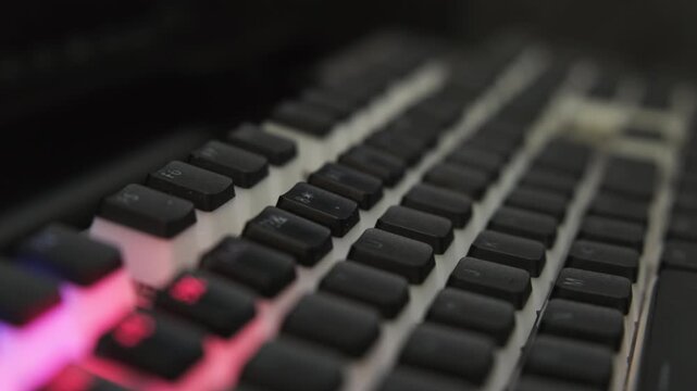 LED backlight mode on computer gaming keyboard in dark room. Dynamic effect wave of different colors runs across keyboard