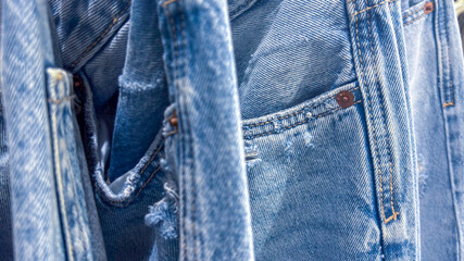 Close-up of faded blue jeans pocket with rivet, seams and folded denim.