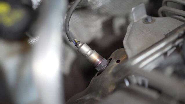Close-up of a car oxygen sensor installed in exhaust manifold.
