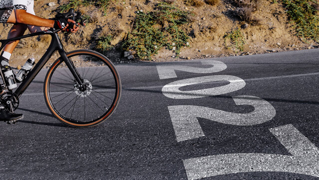 Rider cycling past road marking showing the year 2027 on a winding road