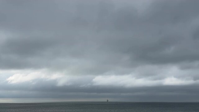雲間から差し込む光と遠くに浮かぶ船