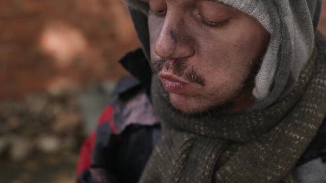 Caucasian young adult homeless man eating sandwich hungrily outdoors in extreme close up shot. Clip fits charity campaigns, poverty awareness videos, and social welfare documentaries