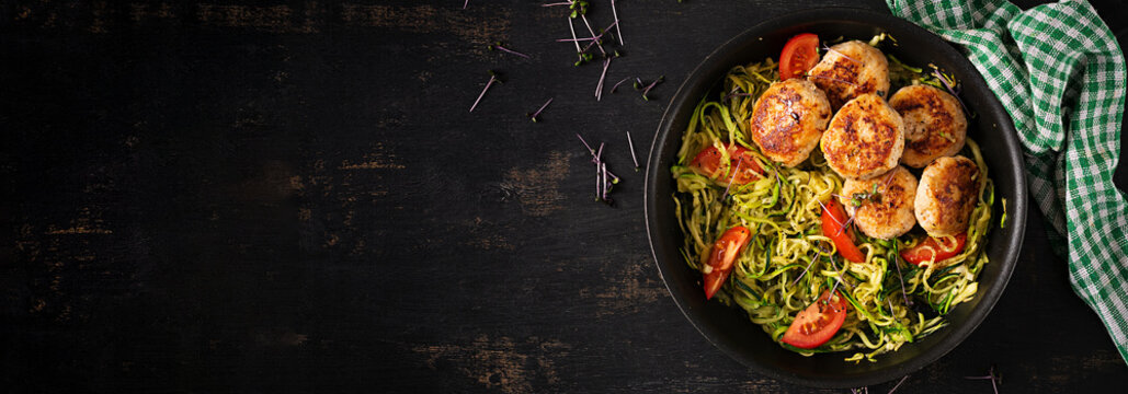 Zucchini spaghetti pasta  with chicken meatballs in pan. Top view. Banner