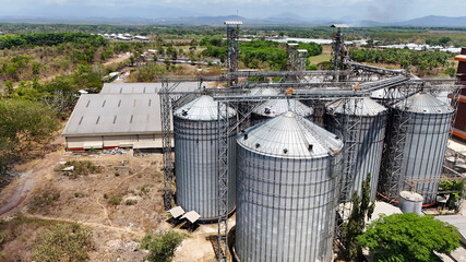Industrial storage facility with metal grain silos and warehouse buildings in a rural area © Salsabila Ariadina