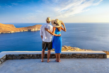 Obraz premium A hugging couple enjoys the elevated view over the ocean during a beautiful summer sunset in the mediterranean, Greece