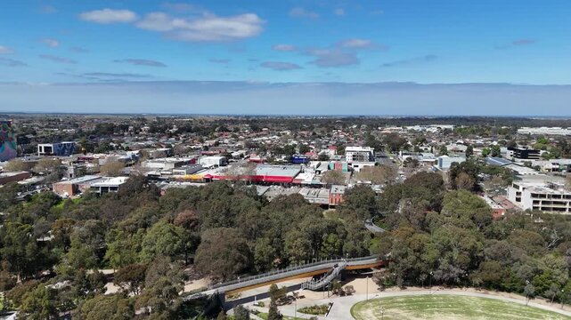 Aerial view of the Werribee town center commercial district, showing local shopping precincts, retail buildings, green parkland and surrounding houses in Melbourne, Victoria, Australia
