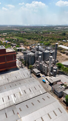 Industrial grain silos and warehouse complex seen from above in a sunny landscape © Salsabila Ariadina