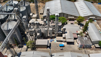 Industrial grain storage facility with metal silos and warehouse buildings viewed from above © Salsabila Ariadina