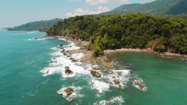 Rocky jungle coast at tropical beach with scenic view of ocean waves in slow motion