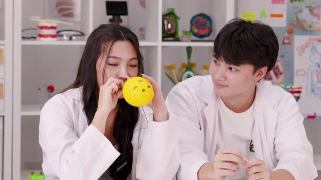 Asian High School Students Laughing During Balloon Experiment in Science Classroom