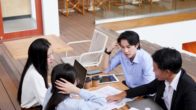 Asian Business Team Brainstorming Outdoors at an Office Terrace Table