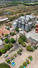 Industrial grain silos and a storage facility with trucks parked in the yard seen from above © Salsabila Ariadina