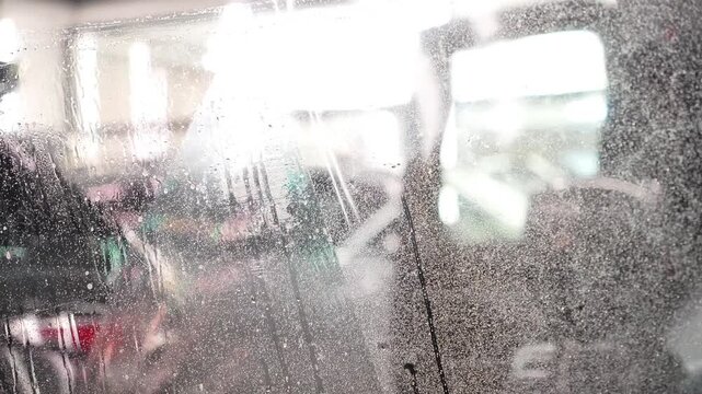 Master installs a protective transparent polyurethane film on a car windshield, before application copiously wetting it with a soapy mixture. Clear wrap protects glass from stone chips, scratches, UV.