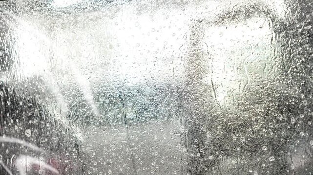 Master installs a protective transparent polyurethane film on a car windshield, before application copiously wetting it with a soapy mixture. Clear wrap protects glass from stone chips, scratches, UV.