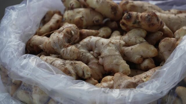 Fresh raw ginger roots displayed in plastic bag at local market stall