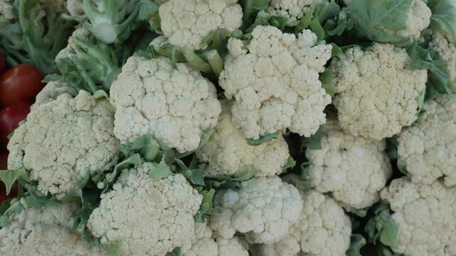 Fresh organic white cauliflowers displayed in red basket at local market stall