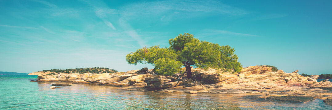 Seascape on a sunny day. Quiet bay with a small rocky island and sandy beach. beautiful lagoon. Lagonisi beach, Halkidiki, Greece