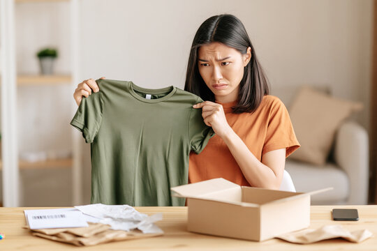 Woman unboxing an online order, looking upset at the delivered item, indicating dissatisfaction with purchase