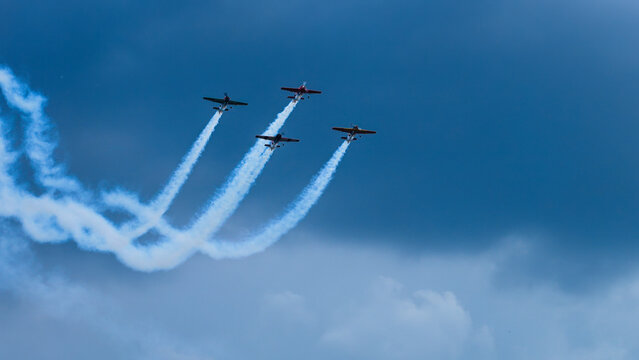 Sports planes fly in formation with smoke trails.