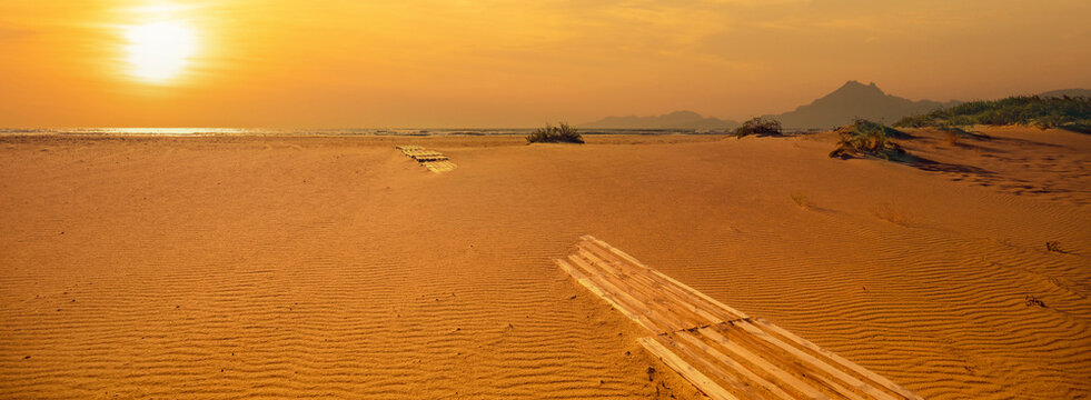 Sandy deserted beach on a sunny day. Wooden walkway on the beach