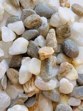 Close up texture of mixed colorful river pebble stones in white, gray, brown and beige tones. Natural smooth quartz and river rocks pile with high detail. Perfect for colorful background, spa, zen gar