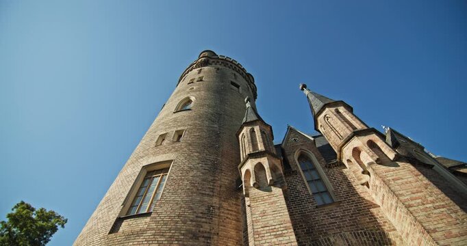 Gothic Revival brickwork and small turrets beside the round shaft of Flatow Tower, Babelsberg Park, Potsdam, Germany.