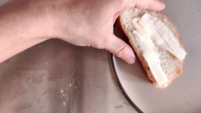 Woman placing a buttered slice of fresh bread onto a white plate