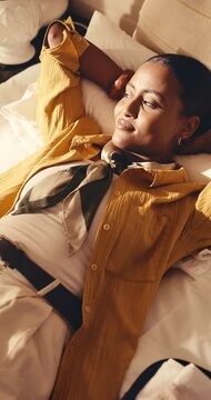 Calm, woman and relax in hotel room with vacation, travel fatigue or reflection for peaceful getaway. Above, person and holiday in accommodation with jet lag exhaustion, thinking and rest on bed.