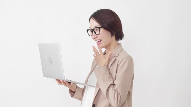 ノートパソコンを使う眼鏡をかけたスーツ姿の女性