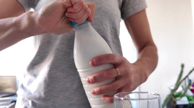 Woman opening a bottle of fresh milk on the kitchen table at home