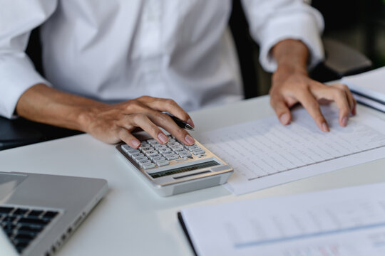 Business executive examining financial data and reviewing paper documents with notebook and pen at office