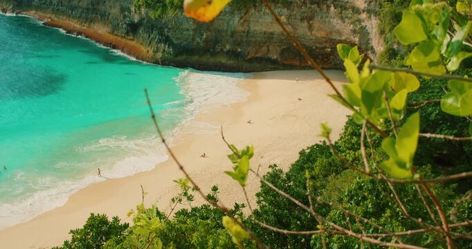 People swimming and sunbathing on sandy shore of beautiful Kelingking beach Nusa Penida Bali