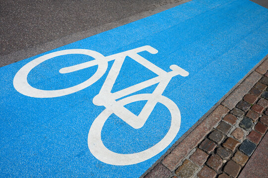 Close-up of a blue-painted bike lane and a white sign in the Old Town of Copenhagen, Denmark.