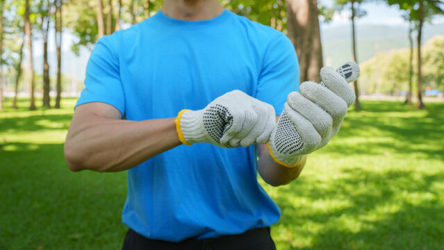 Man putting on protective work gloves outdoors for volunteer park cleanup