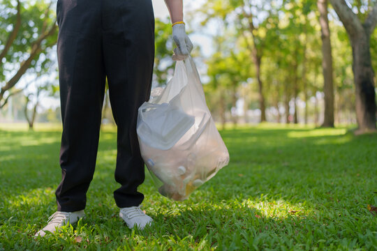 Volunteer holding plastic trash bag in park for environmental cleanup