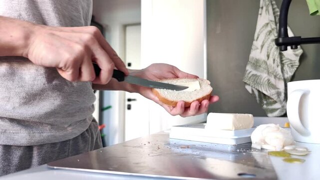 Woman spreading butter over a fresh slice of bread in the home kitchen