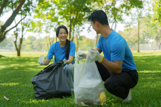 Asian volunteers picking up plastic waste during park cleanup service