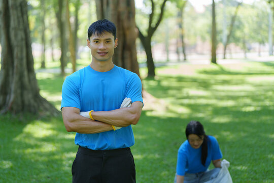 Asian man volunteer posing in park during community environmental cleanup effort