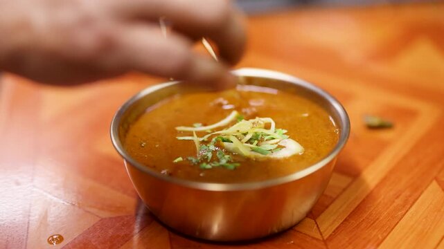 Chef Garnishing Traditional Indian Curry in Metal Bowl