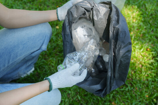 POV of volunteer collecting plastic bottle in garbage bag for eco park cleanup