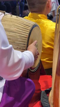 Vertical 4K video showing musician hands slapping and tapping leather heads of horizontal Taphon barrel drum mounted on wooden base.