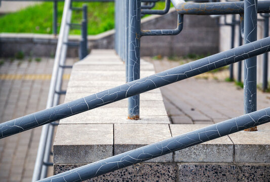 Close up of cracked paint on metal handrail along public concrete staircase structure with copy space
