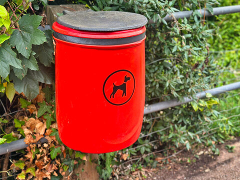 Red Dog Waste Bin Mounted on Fence Line Outdoors